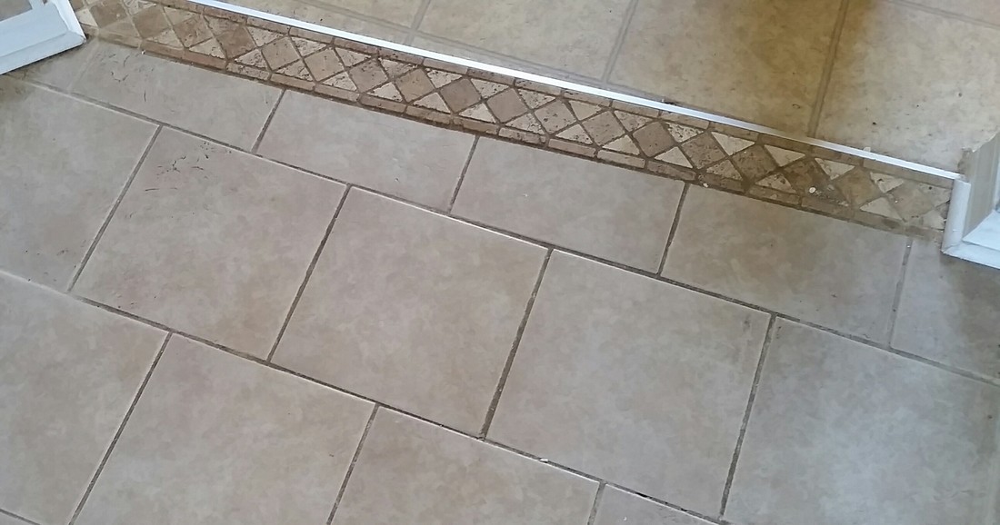 Picture of tile and grout before cleaning by the kitchen entrance where it receives a lot of high traffic 